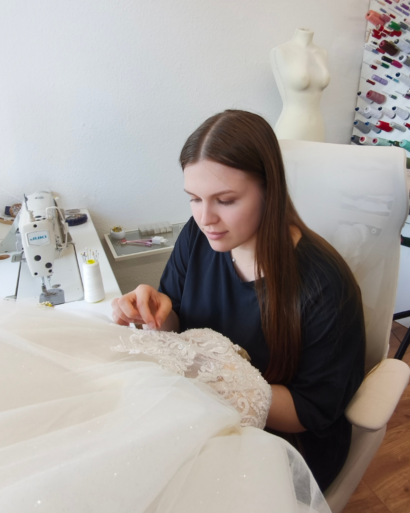 Schneiderin arbeitet an der Spitze eines Brautkleides im Edelweiß Atelier